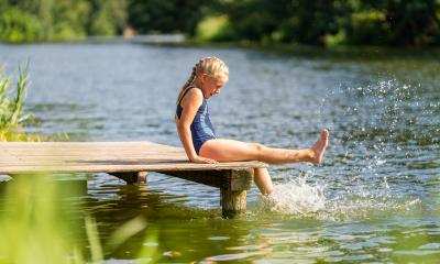 Young girl splashing water with her foot while sitting on a wooden dock by a lake on a sunny day- Stock Photo or Stock Video of rcfotostock | RC Photo Stock