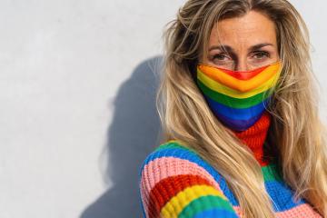 Young lesbian smiling on camera while wearing rainbow face mask to protect others for Coronavirus pandemic - Focus on face- Stock Photo or Stock Video of rcfotostock | RC Photo Stock