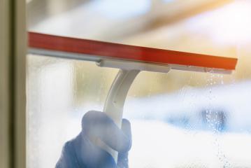 young man is using a rag and squeegee while cleaning windows.- Stock Photo or Stock Video of rcfotostock | RC Photo Stock