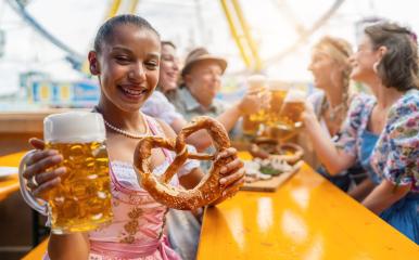 Young woman joyfully holding a beer mug and a pretzel in a beer tent, at Oktoberfest or dult in germany- Stock Photo or Stock Video of rcfotostock | RC Photo Stock