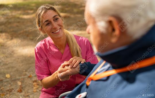 A caregiver in pink scrubs holds the hands of an elderly man wearing a blue jacket and an SOS button. Dementia retirement home concept image  : Stock Photo or Stock Video Download rcfotostock photos, images and assets rcfotostock | RC Photo Stock.: