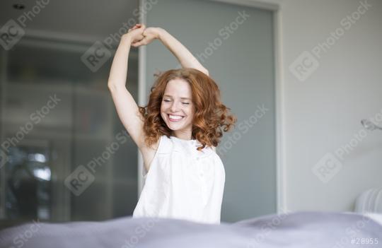 A cheerful red-haired woman stretches her arms happily while standing in a bright, minimalist bedroom, exuding a sense of energy and joy to start the day.  : Stock Photo or Stock Video Download rcfotostock photos, images and assets rcfotostock | RC Photo Stock.: