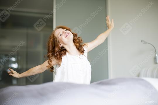 A cheerful woman with red curly hair stretching happily in the morning, standing in a bright bedroom, radiating positive energy and embracing the start of a new day  : Stock Photo or Stock Video Download rcfotostock photos, images and assets rcfotostock | RC Photo Stock.: