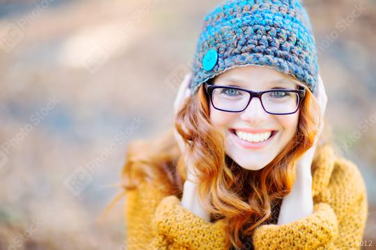 A cheerful woman with red hair wearing glasses, a crocheted blue and brown hat with a button, and a mustard sweater, smiling warmly in an autumn outdoor setting  : Stock Photo or Stock Video Download rcfotostock photos, images and assets rcfotostock | RC Photo Stock.: