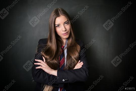 A confident young woman with long brown hair wearing a formal suit and tie, standing with folded arms in front of a blackboard, exuding professionalism and determination
  : Stock Photo or Stock Video Download rcfotostock photos, images and assets rcfotostock | RC Photo Stock.: