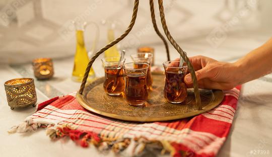 A hand serving Turkish tea on a brass tray with a decorative glass holder and oil bottle in background  : Stock Photo or Stock Video Download rcfotostock photos, images and assets rcfotostock | RC Photo Stock.: