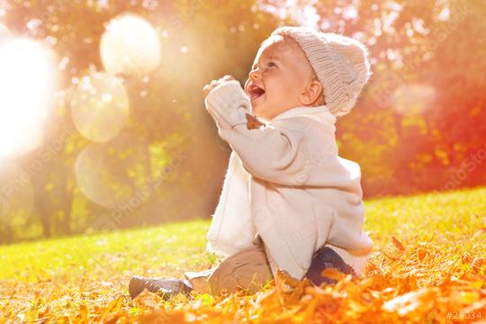 A happy baby sitting outdoors in autumn, surrounded by golden sunlight and falling leaves  : Stock Photo or Stock Video Download rcfotostock photos, images and assets rcfotostock | RC Photo Stock.: