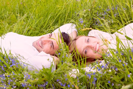 A happy couple lying in a lush green meadow surrounded by wildflowers, enjoying a serene and romantic moment in nature under the warm sunlight  : Stock Photo or Stock Video Download rcfotostock photos, images and assets rcfotostock | RC Photo Stock.: