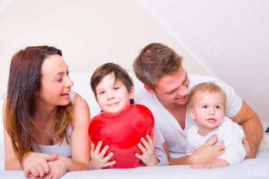 A happy family spending quality time together on a bed, with a young boy holding a large red heart, symbolizing love, bonding, and warmth in a cozy indoor setting
  : Stock Photo or Stock Video Download rcfotostock photos, images and assets rcfotostock | RC Photo Stock.: