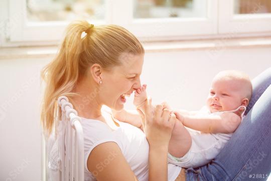 A joyful mother playing with her baby indoors, holding the baby