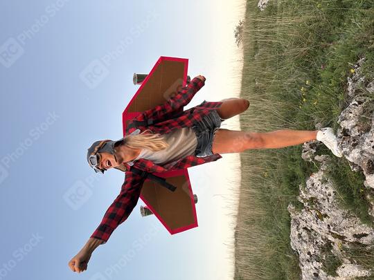 A joyful woman dressed as an aviator with cardboard wings poses on a rock in a grassy field, mimicking flight against a clear blue sky.
  : Stock Photo or Stock Video Download rcfotostock photos, images and assets rcfotostock | RC Photo Stock.: