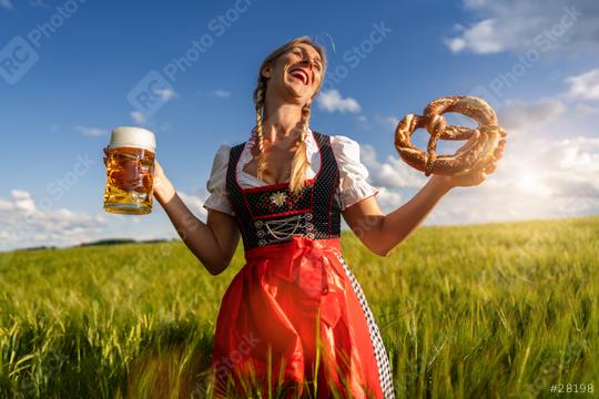 A joyful woman in a traditional Bavarian dress holding a beer and a pretzel in a wheat field celebrating Oktoberfest or dult festival in munich.  : Stock Photo or Stock Video Download rcfotostock photos, images and assets rcfotostock | RC Photo Stock.: