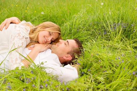 A loving couple lying on lush green grass surrounded by wildflowers, sharing a tender moment with bright smiles, symbolizing love and connection in a natural setting  : Stock Photo or Stock Video Download rcfotostock photos, images and assets rcfotostock | RC Photo Stock.: