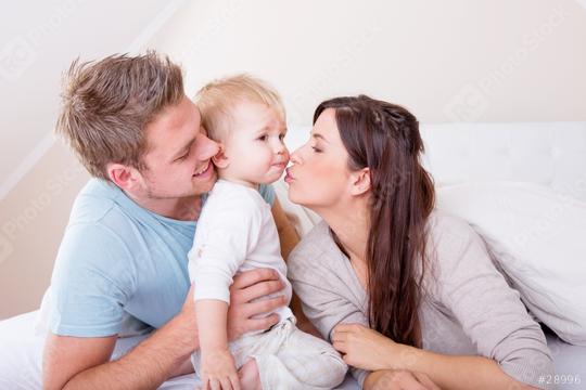 A loving family moment with a mother kissing her toddler, the father holding the child close, all sharing a warm, happy interaction in a cozy home environment filled with affection.  : Stock Photo or Stock Video Download rcfotostock photos, images and assets rcfotostock | RC Photo Stock.: