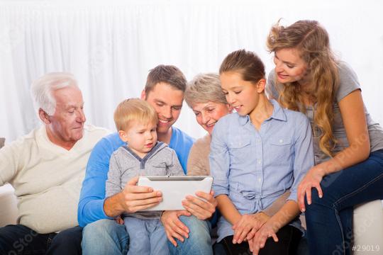 A multi-generational family gathered together on a couch, smiling and enjoying time with a digital tablet, showing bonding, love, and connection in a cozy indoor setting  : Stock Photo or Stock Video Download rcfotostock photos, images and assets rcfotostock | RC Photo Stock.: