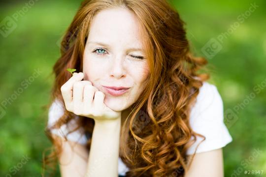 A playful young woman with red curly hair winks while holding a small clover leaf in a lush green outdoor setting, radiating charm, nature, and happiness
  : Stock Photo or Stock Video Download rcfotostock photos, images and assets rcfotostock | RC Photo Stock.: