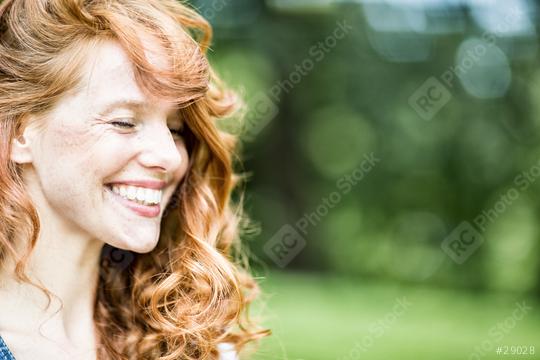 A red-haired woman with curly hair, smiling brightly in a natural outdoor setting, radiating happiness and beauty, with a blurred green background enhancing the serene mood  : Stock Photo or Stock Video Download rcfotostock photos, images and assets rcfotostock | RC Photo Stock.:
