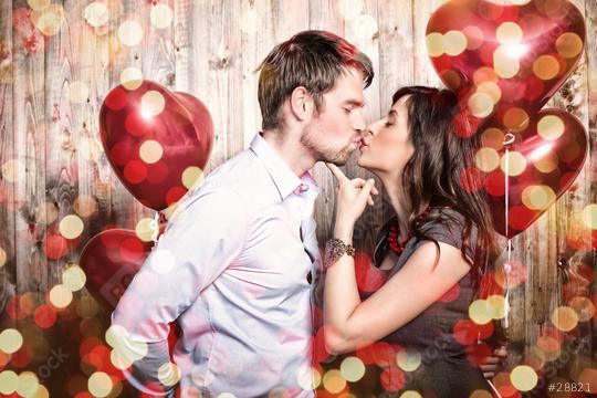 A romantic couple kissing with red heart-shaped balloons in a festive background featuring wooden planks and golden bokeh lights  : Stock Photo or Stock Video Download rcfotostock photos, images and assets rcfotostock | RC Photo Stock.: