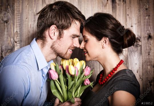 A romantic couple shares an intimate moment with their foreheads touching, holding a colorful bouquet of tulips against a rustic wooden background, expressing love and tenderness  : Stock Photo or Stock Video Download rcfotostock photos, images and assets rcfotostock | RC Photo Stock.: