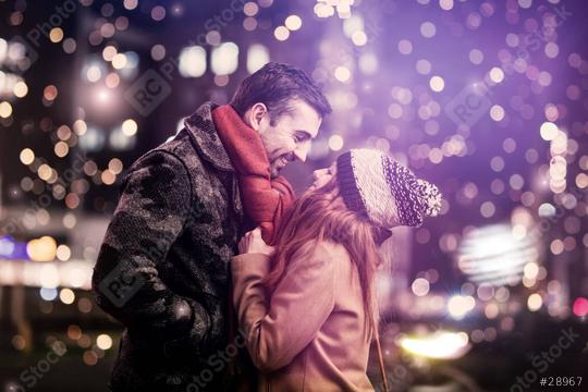 A romantic couple sharing a warm moment outdoors at night, surrounded by festive lights and a magical atmosphere, dressed in cozy winter clothing and smiling at each other  : Stock Photo or Stock Video Download rcfotostock photos, images and assets rcfotostock | RC Photo Stock.: