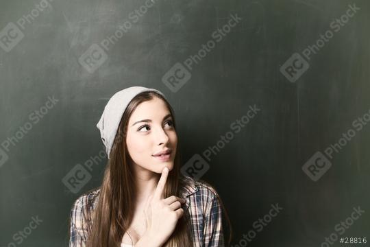 A thoughtful young woman with long hair wearing a gray beanie and plaid shirt, looking upwards against a green chalkboard background, symbolizing creativity, curiosity, and inspiration  : Stock Photo or Stock Video Download rcfotostock photos, images and assets rcfotostock | RC Photo Stock.: