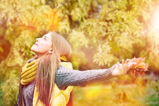 A young woman enjoying autumn, wearing a yellow scarf and vest, holding fall leaves, with sunlight streaming through golden foliage, embracing the peaceful beauty of the season  : Stock Photo or Stock Video Download rcfotostock photos, images and assets rcfotostock | RC Photo Stock.: