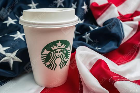 AACHEN, GERMANY FEBRUARY, 2017: Starbucks take away coffee cup on a america flag.  Starbucks is the largest coffeehouse company in the world.  : Stock Photo or Stock Video Download rcfotostock photos, images and assets rcfotostock | RC Photo Stock.: