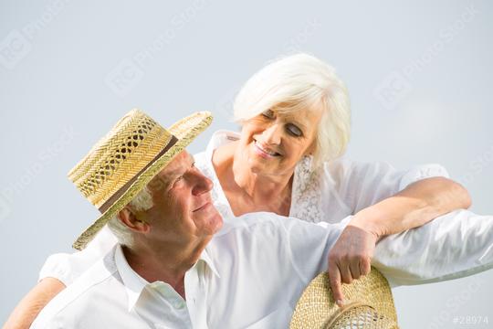 An affectionate senior couple smiling at each other, wearing white outfits and straw hats, enjoying a serene moment together, symbolizing love, companionship, and happiness in their golden years  : Stock Photo or Stock Video Download rcfotostock photos, images and assets rcfotostock | RC Photo Stock.: