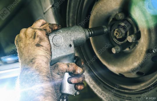 Auto mechanic changing a car tire in mechanics garage and using a electric drill to loosen the bolts. Repair service. authentic close-up shot   : Stock Photo or Stock Video Download rcfotostock photos, images and assets rcfotostock | RC Photo Stock.: