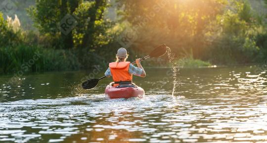 Back view of a woman paddling a kayak on a river, surrounded by lush greenery and bathed in sunset light. Kayak Water Sports concept image  : Stock Photo or Stock Video Download rcfotostock photos, images and assets rcfotostock | RC Photo Stock.: