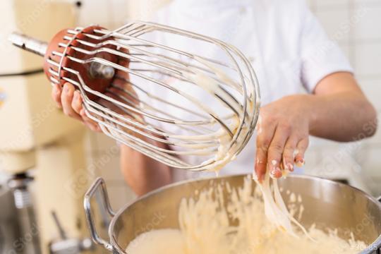 baker cleans batter off a large whisk attachment over a mixing bowl, showcasing the process of preparing batter in a professional kitchen environment  : Stock Photo or Stock Video Download rcfotostock photos, images and assets rcfotostock | RC Photo Stock.: