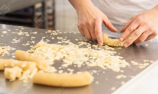 Baker coating cookie dough in almond slices on a work surface, preparing the dough for baking in a bakery, with hands arranging almond-covered dough in a professional setting  : Stock Photo or Stock Video Download rcfotostock photos, images and assets rcfotostock | RC Photo Stock.: