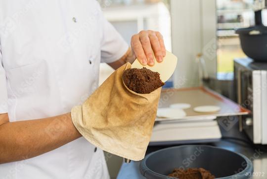 baker fills a piping bag with gingerbread dough using a scraper, preparing for the next step of piping the mixture onto wafers in a professional kitchen setting  : Stock Photo or Stock Video Download rcfotostock photos, images and assets rcfotostock | RC Photo Stock.: