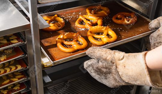 Baker getting fresh bavarian pretzels out of oven on baking sheet  : Stock Photo or Stock Video Download rcfotostock photos, images and assets rcfotostock | RC Photo Stock.: