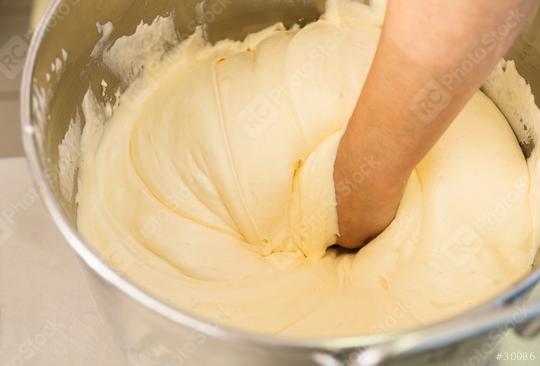 Baker hand mixes thick cake batter in a large stainless steel bowl, showcasing the texture and consistency of the batter during the baking process in a professional kitchen setting  : Stock Photo or Stock Video Download rcfotostock photos, images and assets rcfotostock | RC Photo Stock.: