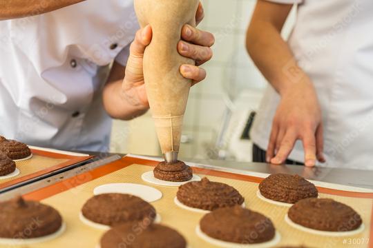 baker is piping gingerbread dough onto baking wafers using a piping bag, preparing the gingerbread rounds on a silicone mat for baking in a professional kitchen  : Stock Photo or Stock Video Download rcfotostock photos, images and assets rcfotostock | RC Photo Stock.: