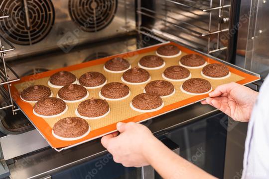 baker places a tray of raw gingerbread rounds on baking wafers into the oven for baking, showcasing the preparation process in a professional bakery kitchen setting  : Stock Photo or Stock Video Download rcfotostock photos, images and assets rcfotostock | RC Photo Stock.: