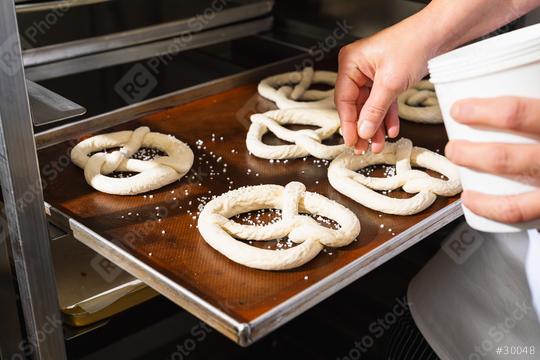 Baker salting raw pretzels on a baking sheet  : Stock Photo or Stock Video Download rcfotostock photos, images and assets rcfotostock | RC Photo Stock.: