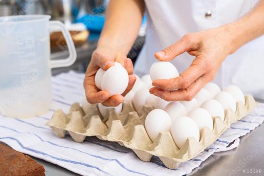 Baker selecting eggs from a carton in a bakery, preparing ingredients for baking in a professional kitchen environment  : Stock Photo or Stock Video Download rcfotostock photos, images and assets rcfotostock | RC Photo Stock.: