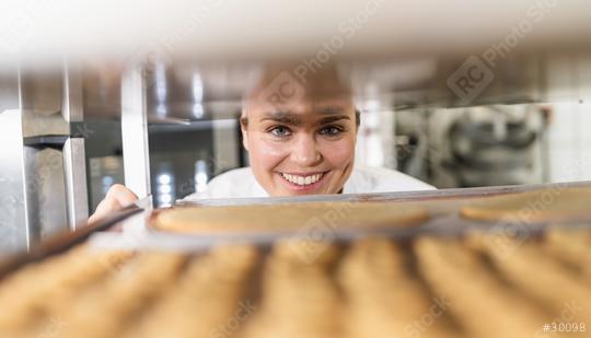 Baker smiling while checking trays of freshly baked cookies on a cooling rack in a bakery, inspecting the baked goods in a professional baking environment  : Stock Photo or Stock Video Download rcfotostock photos, images and assets rcfotostock | RC Photo Stock.: