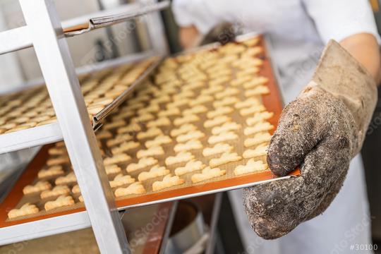 Baker wearing a glove and placing a tray of freshly baked cookies on a cooling rack in a bakery, using a silicone mat to support the cookies in a professional baking environment  : Stock Photo or Stock Video Download rcfotostock photos, images and assets rcfotostock | RC Photo Stock.: