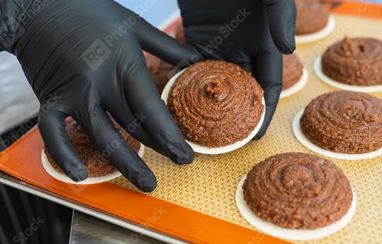 baker wearing black gloves carefully handles gingerbread dough piped onto a round wafer, arranging the treats on a silicone baking mat in preparation for baking  : Stock Photo or Stock Video Download rcfotostock photos, images and assets rcfotostock | RC Photo Stock.:
