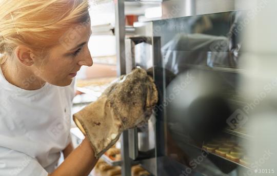 Baker woman at the oven with glove controls baking in the oven with glass doors in the bakery  : Stock Photo or Stock Video Download rcfotostock photos, images and assets rcfotostock | RC Photo Stock.:
