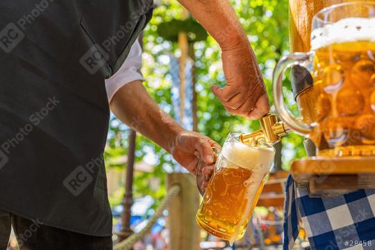 Bavarian man in apron is pouring a large lager beers in tap from wooden beer barrel in the beer garden. Background for Oktoberfest or Wiesn, folk or beer festival  : Stock Photo or Stock Video Download rcfotostock photos, images and assets rcfotostock | RC Photo Stock.: