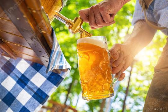 Bavarian man in leather trousers is pouring a large lager beer in tap from wooden beer barrel in the beer garden. Background for Oktoberfest or Wiesn, folk or beer festival (German for: O’zapft is!)   : Stock Photo or Stock Video Download rcfotostock photos, images and assets rcfotostock | RC Photo Stock.: