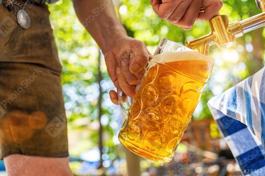 Bavarian man in leather trousers is pouring a large lager beer in tap from wooden beer barrel in the beer garden. Background for Oktoberfest or Wiesn, folk or beer festival (German for: O’zapft is!)   : Stock Photo or Stock Video Download rcfotostock photos, images and assets rcfotostock | RC Photo Stock.: