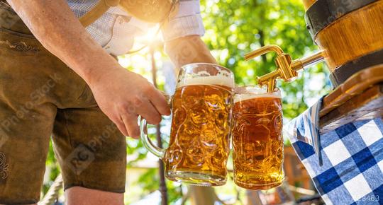 Bavarian man in leather trousers is pouring large lager beers in tap from wooden beer barrel in the beer garden. Background for Oktoberfest or Wiesn, folk or beer festival (German for: O’zapft is!)   : Stock Photo or Stock Video Download rcfotostock photos, images and assets rcfotostock | RC Photo Stock.: