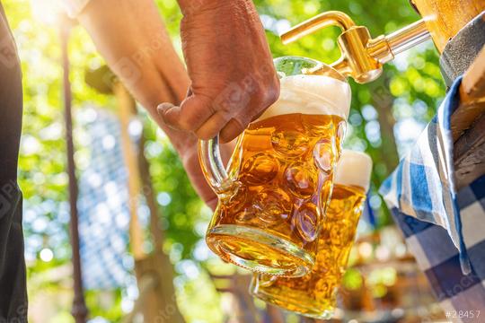 Bavarian man is pouring large lager beers in tap from wooden beer barrel in the beer garden. Background for Oktoberfest or Wiesn, folk or beer festival (German for: O’zapft is!)   : Stock Photo or Stock Video Download rcfotostock photos, images and assets rcfotostock | RC Photo Stock.: