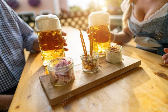 Bavarian Obatzda with pretzels and radishes and beer mugs, man and young woman in tracht in the background at beer garden or oktoberfest, Munich, Germany  : Stock Photo or Stock Video Download rcfotostock photos, images and assets rcfotostock | RC Photo Stock.: