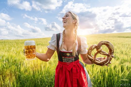 Bavarian woman in traditional German tracht outfit, holding a beer and pretzel in a sunny field celebrating Oktoberfest or dult festival in munich.  : Stock Photo or Stock Video Download rcfotostock photos, images and assets rcfotostock | RC Photo Stock.: